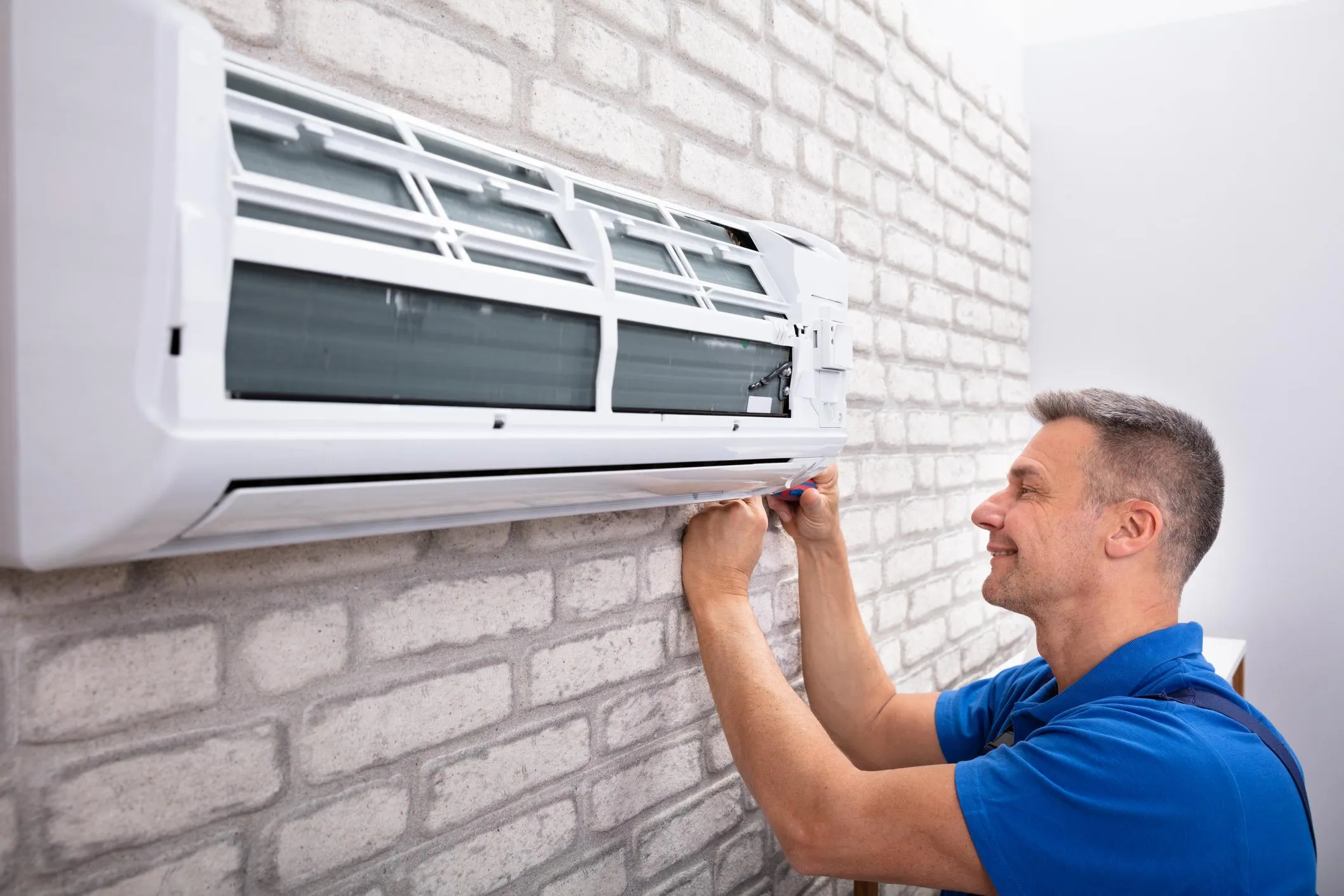 Male AC technician checking an outdoor unit with gauges and professional repair tools