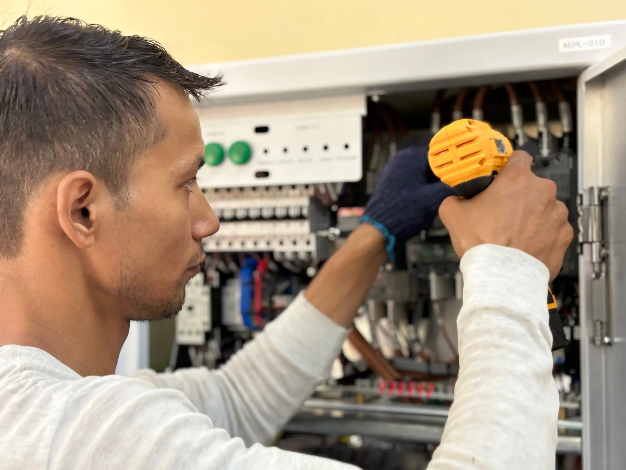 Male electrician working on an electrical distribution panel with professional tools